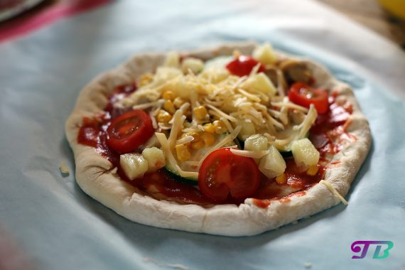 Minipizza mit Tomate, Ananas, Zucchini und Käse